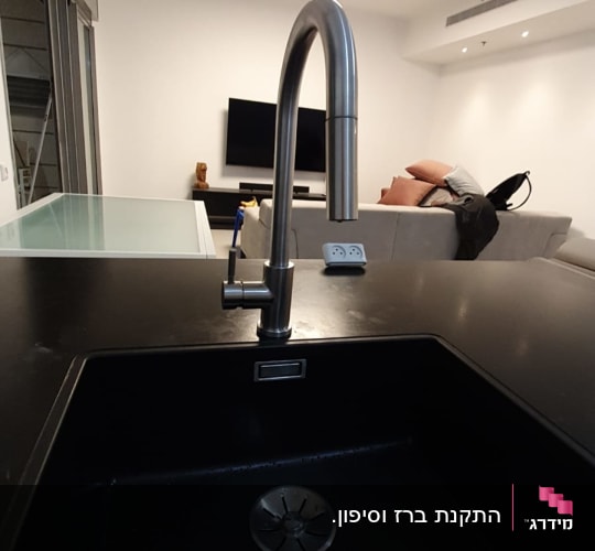 ברז נירוסטה מעל כיור שחור במטבח מודרני